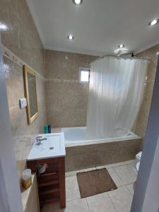 a bathroom with a tub and a sink and a shower at Nomade bedbox Hostel in El Chalten