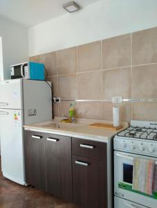 Cabaña 25 San Rafael في سان رافاييل: مطبخ مع موقد وثلاجة بيضاء