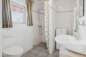 a white bathroom with a sink and a toilet at Calm Holiday Home With Great Outings in Kollund +22 photos