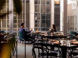eine Gruppe von Menschen, die an einem Tisch in einem Restaurant sitzen in der Unterkunft Swissotel Sydney in Sydney