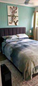 Una cama en un dormitorio con una pared azul. en Darwin Cottage, en Kerikeri