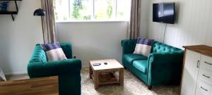 a living room with two green chairs and a table at Darwin Cottage in Kerikeri