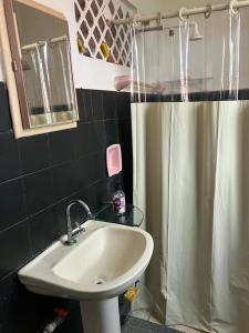 a bathroom with a sink and a shower curtain at Quarto aconchegante no centro in São Luís