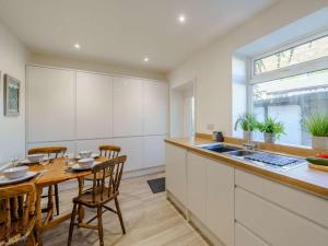 格伦里丁2 Bed in Glenridding 85425的厨房配有白色橱柜和木桌及椅子