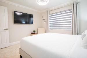 Un dormitorio con una cama blanca y un televisor de pantalla plana. en Longwood Private Suite - Near Orlando - Modern, Private Entrance, Fast WiFi, en Orlando