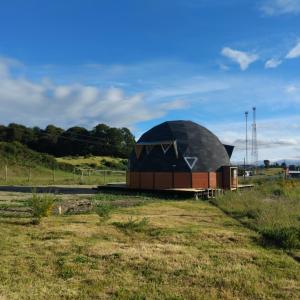 een gebouw met een koepel in een veld naast een veld bij Domo rústico Puacura Castro- Dalcahue in Dalcahue