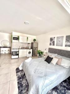 a white bedroom with a large bed and a kitchen at Loft natural - Zona rio - Turismo! in Rosario