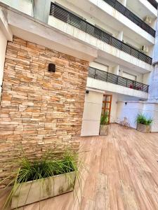 a large lobby with a stone wall and plants at Loft natural - Zona rio - Turismo! in Rosario