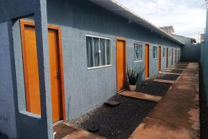 Una hilera de puertas naranjas en un edificio azul. en Apartamento Confortável Novo com Ar condicionado, en Tangará da Serra