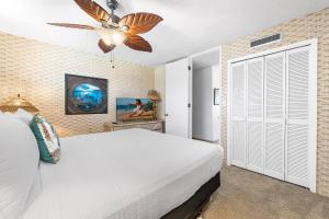 ein Schlafzimmer mit einem weißen Bett und einem Deckenventilator in der Unterkunft Kona Alii 504 in Kailua-Kona + 41 Fotos