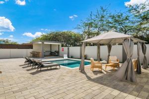 eine Terrasse mit einem Pool und einem Pavillon in der Unterkunft Monserat 33Q in Palm-Eagle Beach