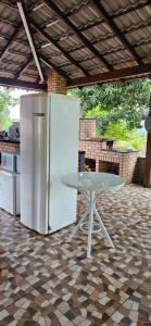 ein weißer Kühlschrank und ein Tisch auf einer Terrasse in der Unterkunft Refúgio Romântico com Pet Friendly 38min de ÁGUAS CLARAS BRASÍLIA in Brasilia