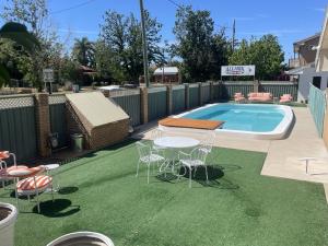 eine Terrasse mit Tisch und Stühlen neben einem Pool in der Unterkunft Albury Allawa Motor Inn in Albury