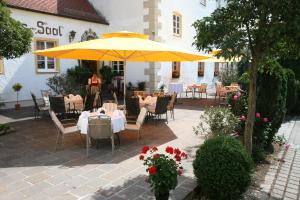 un patio con mesas y sillas y una sombrilla amarilla en Schlosswirt Etting en Ingolstadt