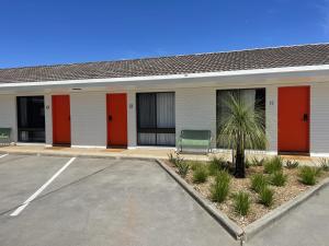 ein Gebäude mit roten Türen und einer grünen Bank auf einem Parkplatz in der Unterkunft Albury Allawa Motor Inn in Albury