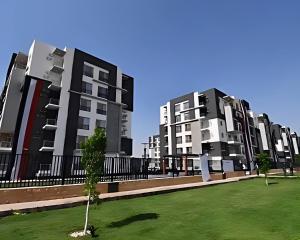 a row of tall apartment buildings with a green lawn at Elegant Apartment at Sheikh Zayed Compound in Sheikh Zayed