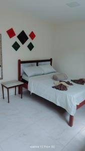 una camera da letto con un letto con un tavolo e immagini appese al muro di Suíte península de Búzios a Búzios