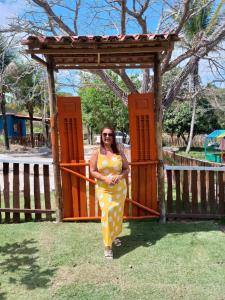 Eine Frau in einem gelben Kleid steht vor einem Tor in der Unterkunft Chácara Belas Artes in Sairé + 12 Fotos