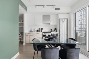 a kitchen with a glass table and black chairs at Modern Downtown Retreat 3BR Condo with Patio in Toronto