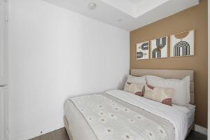 a bedroom with a white bed with two paintings on the wall at Modern Downtown Retreat 3BR Condo with Patio in Toronto
