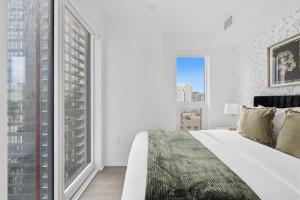 a bedroom with a white bed and large windows at Modern Downtown Retreat 3BR Condo with Patio in Toronto +28 photos