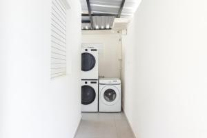 Ocean Park Studio Pool at Riviera Villa في سان خوان: غسالتين وغسالة ومجفف في ممر أبيض