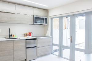 Ocean Park Studio Pool at Riviera Villa في سان خوان: مطبخ مع دواليب بيضاء وميكرويف