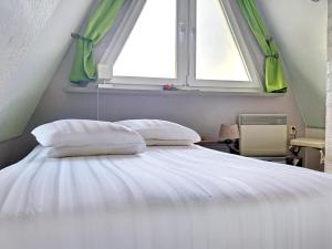een slaapkamer met een wit bed met een raam bij Moni in Hüttenrode