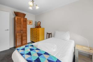 a bedroom with a white bed and a yellow dresser at Beach Retreat in Warrnambool