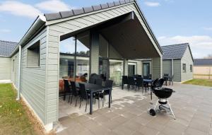 eine überdachte Terrasse mit einem Tisch, Stühlen und einem Grill in der Unterkunft Cozy Home In Glesborg With Sauna in Fjellerup + 12 Fotos