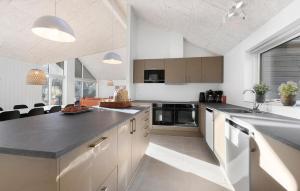 eine Küche mit weißen Schränken und einer schwarzen Arbeitsplatte in der Unterkunft Cozy Home In Glesborg With Sauna in Fjellerup