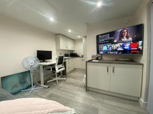 a bedroom with a large tv and a desk with a computer at Moore Place in Houghton Regis