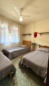 ein Schlafzimmer mit drei Betten und einem Deckenventilator in der Unterkunft Quarto das Araras Hostel Ninho das Harpias in Divino de São Lourenço + 54 Fotos