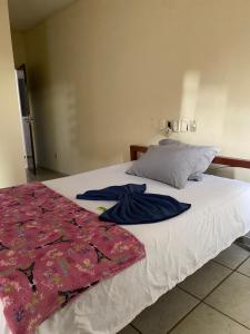 a bed with white sheets and a blue shirt on it at Quarto econômico no centro in Sete Lagoas