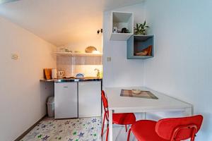 Una pequeña cocina con una mesa blanca y sillas rojas. en Studio Trpanj 257c, en Trpanj