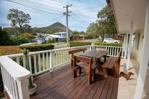 a wooden deck with a wooden table and bench on a house at Illaroo House in Shoal Bay