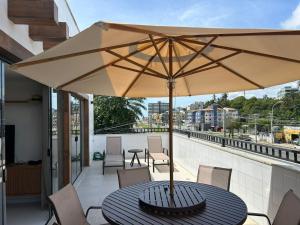 a table with an umbrella on a balcony at Cobertura pé na areia, 3 suítes e área externa in Ilhéus