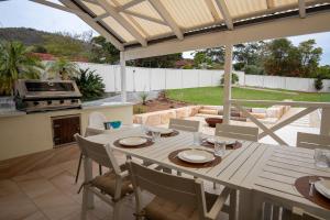 a patio with a table with chairs and a grill at Illaroo House in Shoal Bay