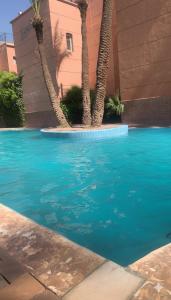 een blauw zwembad met palmbomen naast een gebouw bij Riad Nahara in Marrakesh