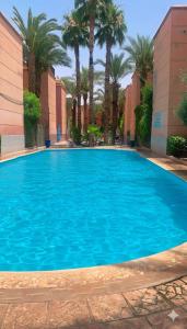 een groot blauw zwembad met palmbomen en gebouwen bij Riad Nahara in Marrakesh