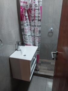 Un baño con lavabo y cortina de ducha. en Departamento Rojavitiva, en General Belgrano