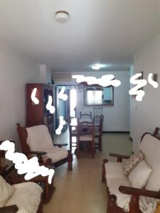 Departamento Luz في كونسيبسيون ديل أوروغواي: غرفة معيشة مع كراسي وطاولة عليها سحب بيضاء