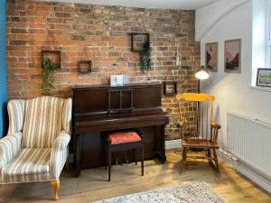 sala de estar con piano y silla en Lodge Yard Barn, en Roecliffe