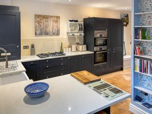 Una cocina con gabinetes negros y encimera. en Lodge Yard Barn, en Roecliffe