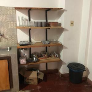 eine Küche mit Holzregalen mit Töpfen und Pfannen in der Unterkunft Casa Angela María in Caacupé