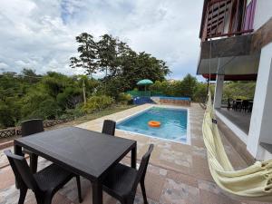 a patio with a table and a hammock next to a pool at Casa campestre Montenegro Quindio in Montenegro