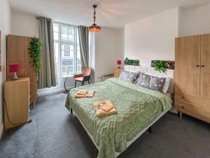 a bedroom with a bed with a green comforter at Flat One in Weymouth