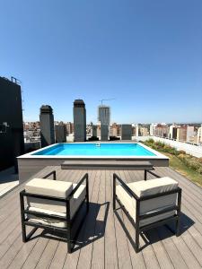 zwei Stühle und ein Tisch auf einem Dach mit einem Pool in der Unterkunft Petit Premium Nueva Cba - Oulton in Cordoba