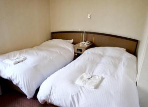 two beds in a hotel room with white sheets at Tetora Higashimuroran in Muroran +24 photos