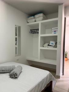 a bedroom with a bed with white walls and shelves at Apartamento Roldanillo in Roldanillo
